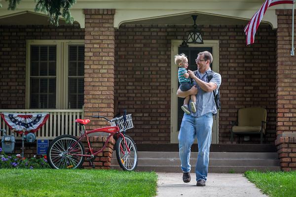 Student with child walking down the sidewalk in front of Roudebush Cottage